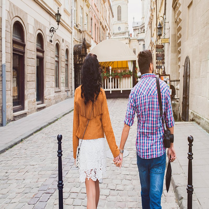 young couple in love traveling, vintage style, europe vacation, honey moon, old city center, happy positive mood, holding hands, walking together in street, view from back